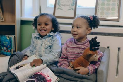 A baby an adult play with a sensory tuff tray