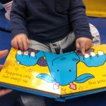 Child reading a dragon book at Play B C Preschool