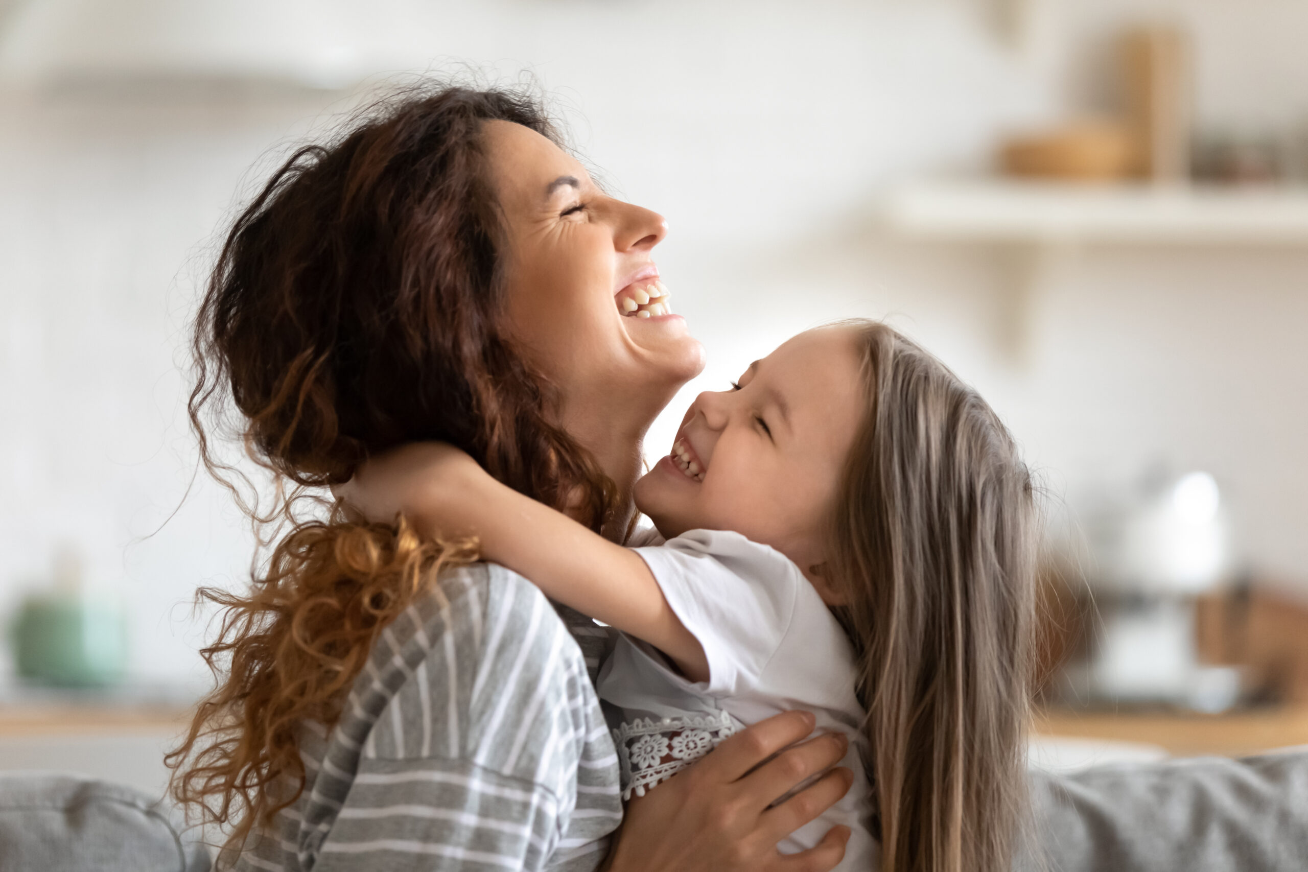 Close up overjoyed young mother and daughter hugging and laughing