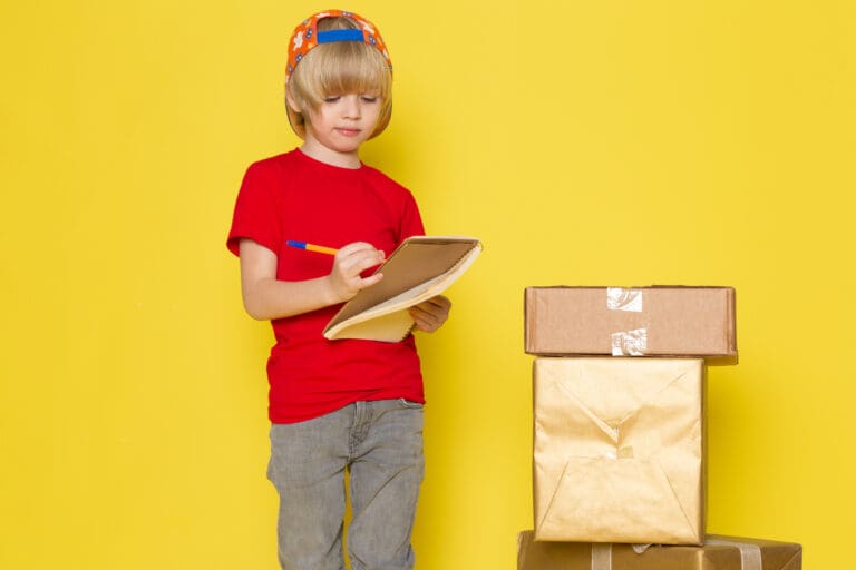 front-view-little-boy-red-t-shirt-colorful-cap-grey-jeans-holding-box-yellow-background